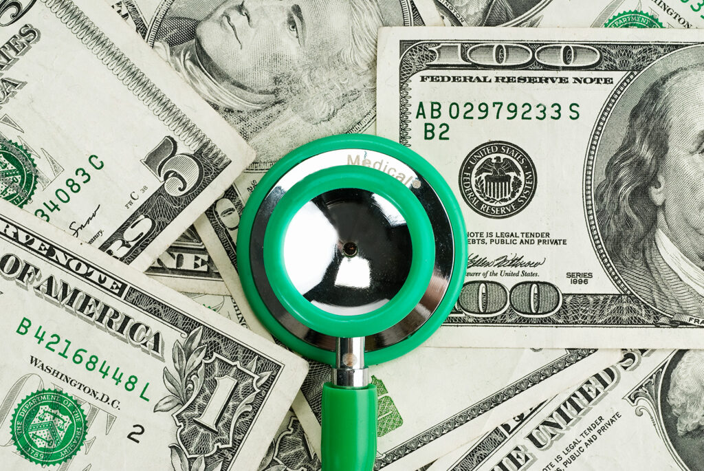 Green Stethoscope on top of money | EnableComp Available Nationwide