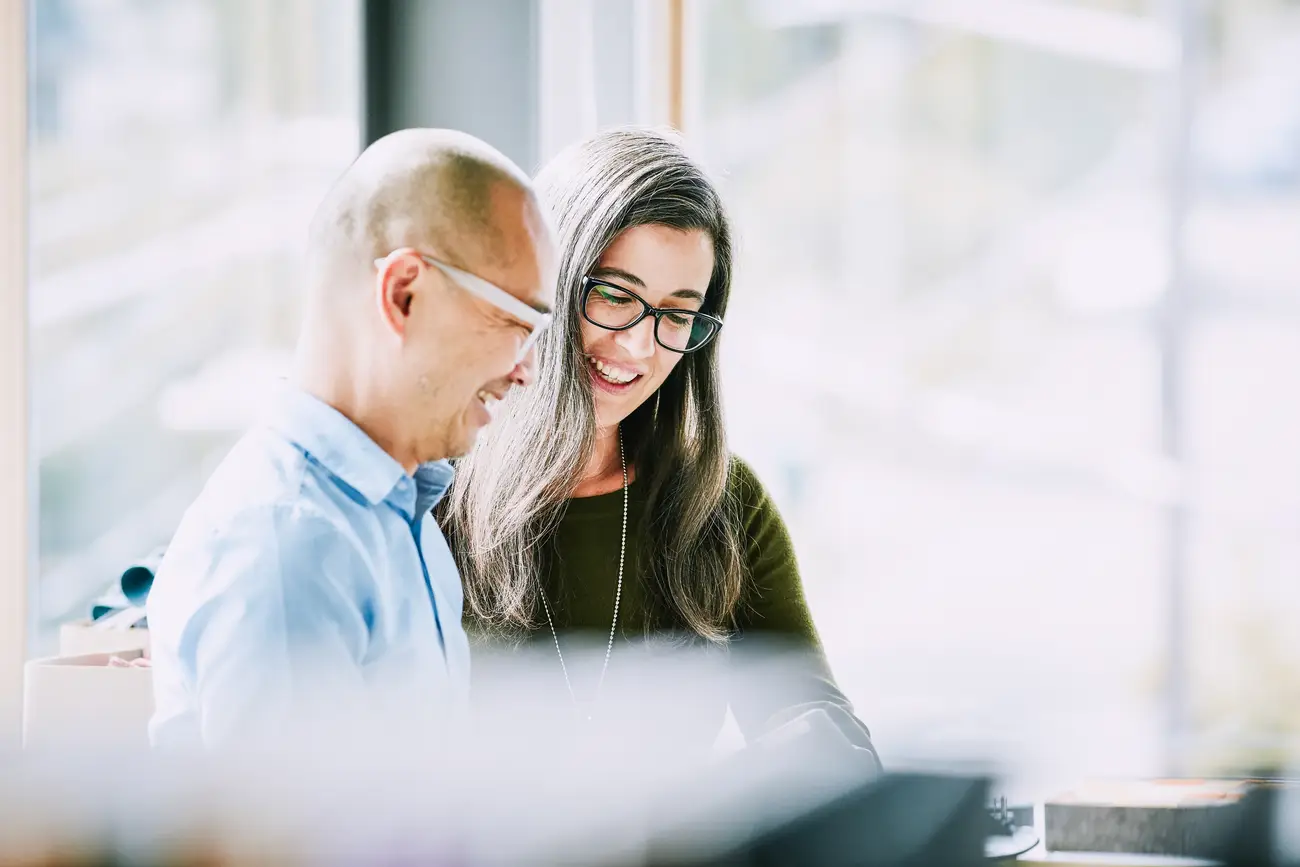 Two people sitting beside each other looking down at documents | EnableComp is available across the United States.